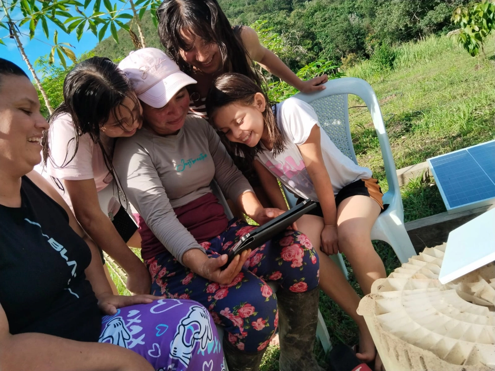 Mujeres rurales consultan una tableta junto a una solución de conectividad alimentada por energía solar